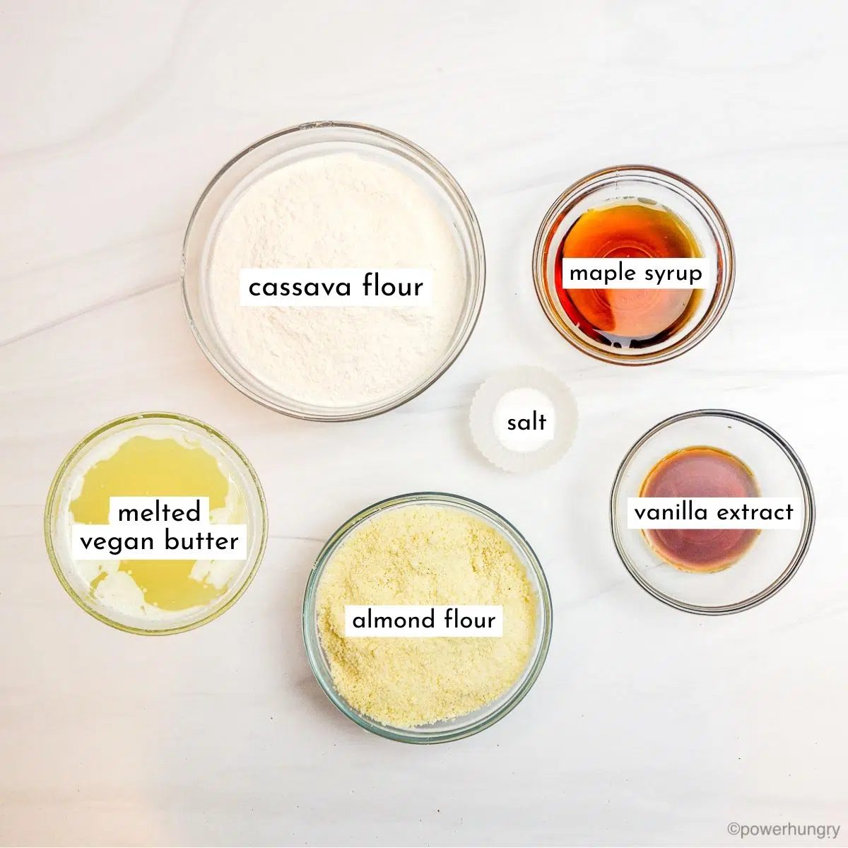 ingredients for cassava flour shortbread cookies, all in glass bowls on a marble countertop
