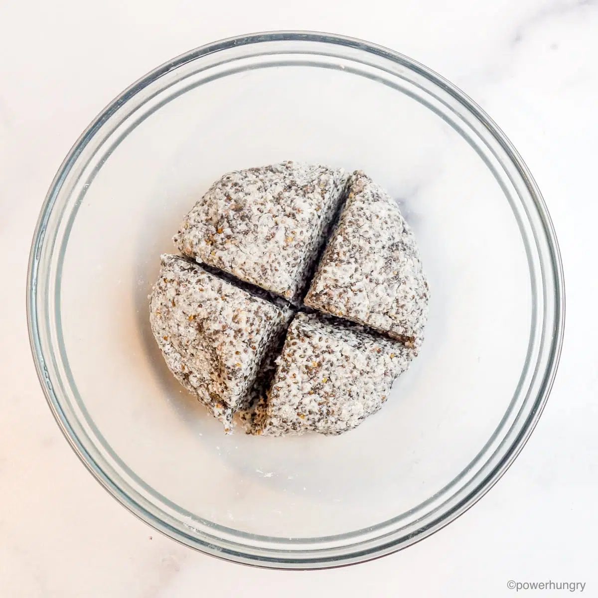 chia tortilla dough in a glas bowl cut into 4 equal pieces
