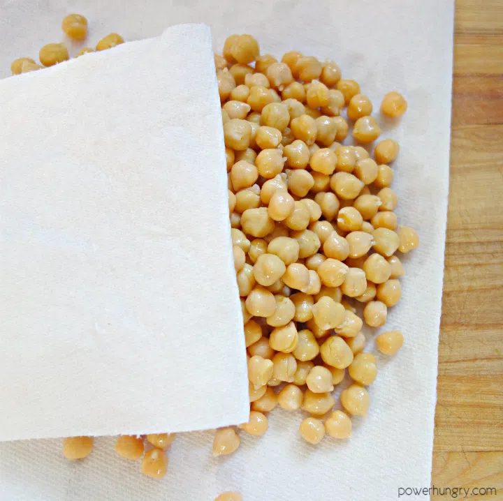 rinsed and drained chickpeas (garbanzo beans) being blotted between sheets of paper towels to remove moisture