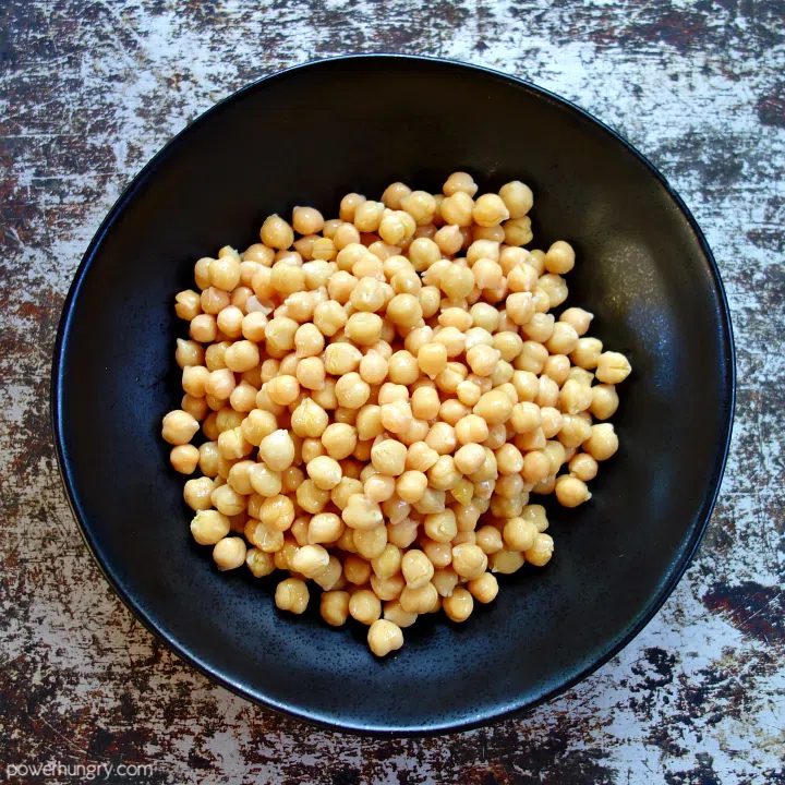 overhead shot of a black ceramc bowl filled with drained chickpeas (garbanzo beans)