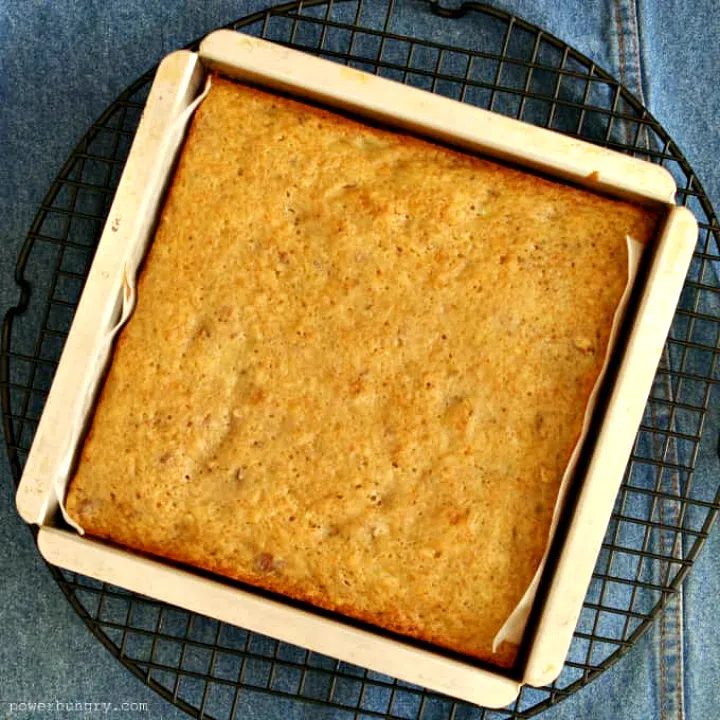 overhead shot of chickpea flour banana cake ina silver baking pan, set atop a black wire cooling rack