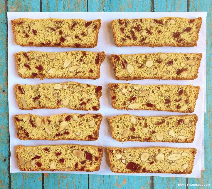 chickpea flour biscotti thins on parchment paper atop a blue painted aged board