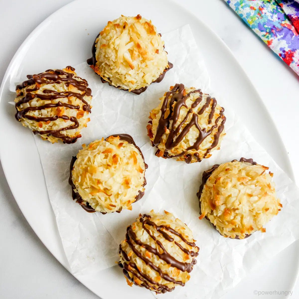 vegan chickpea coconut macaroons coated with dark chocolate, sitting on a white plate