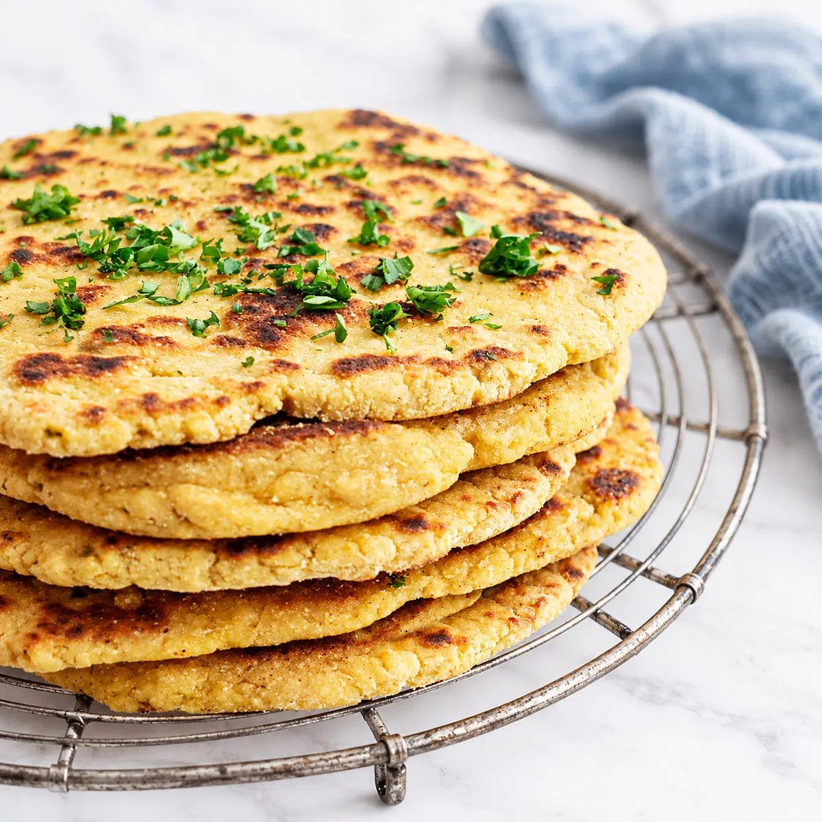 chickpea flour naan on a cooling rack, showing a side view of the naan