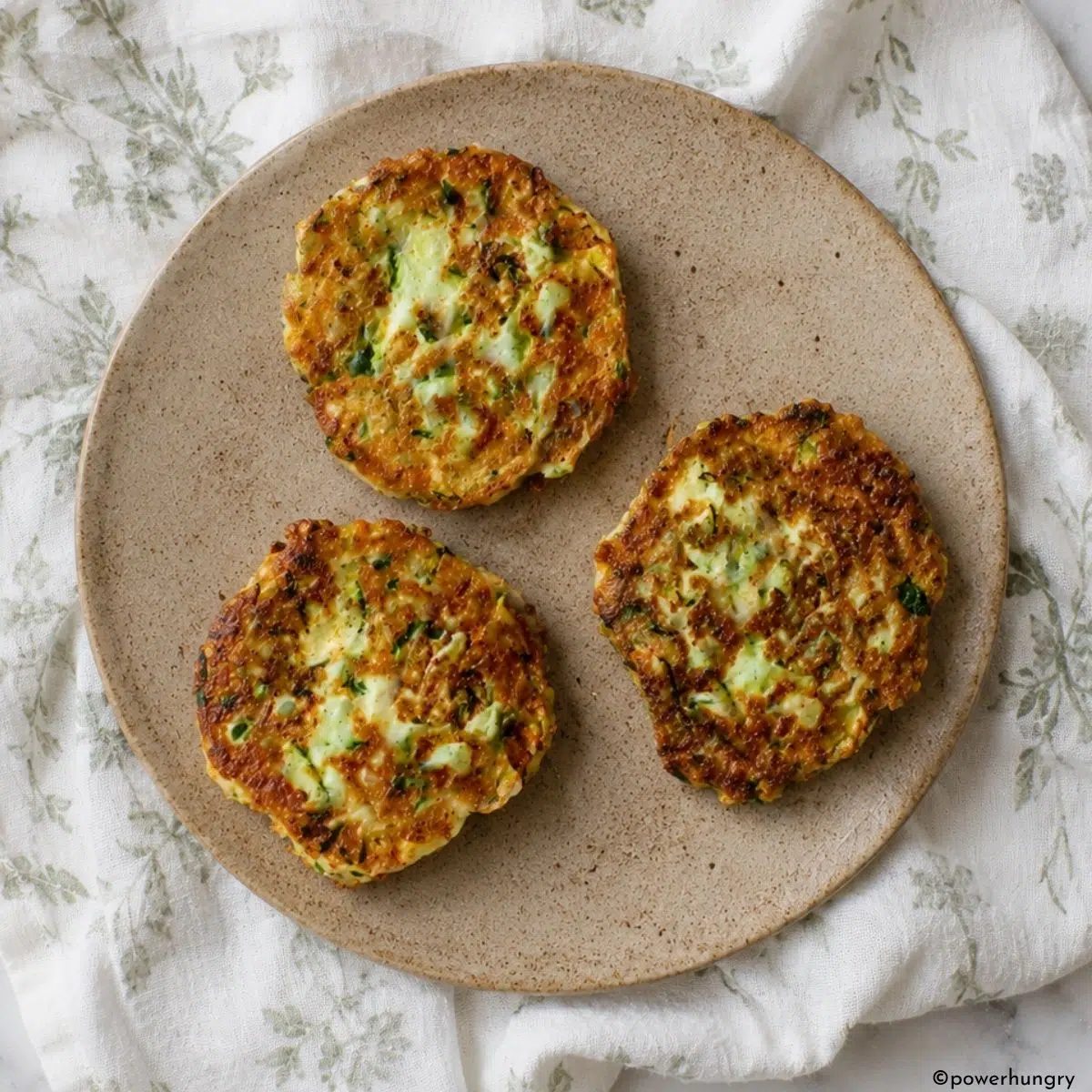overhead shot of stoneware plate with three vegan zucchini chickpea flour fritters
