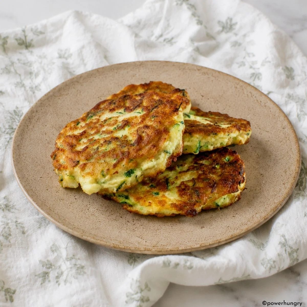 chickpea zucchini fritters stacked on a tan stoneware plate