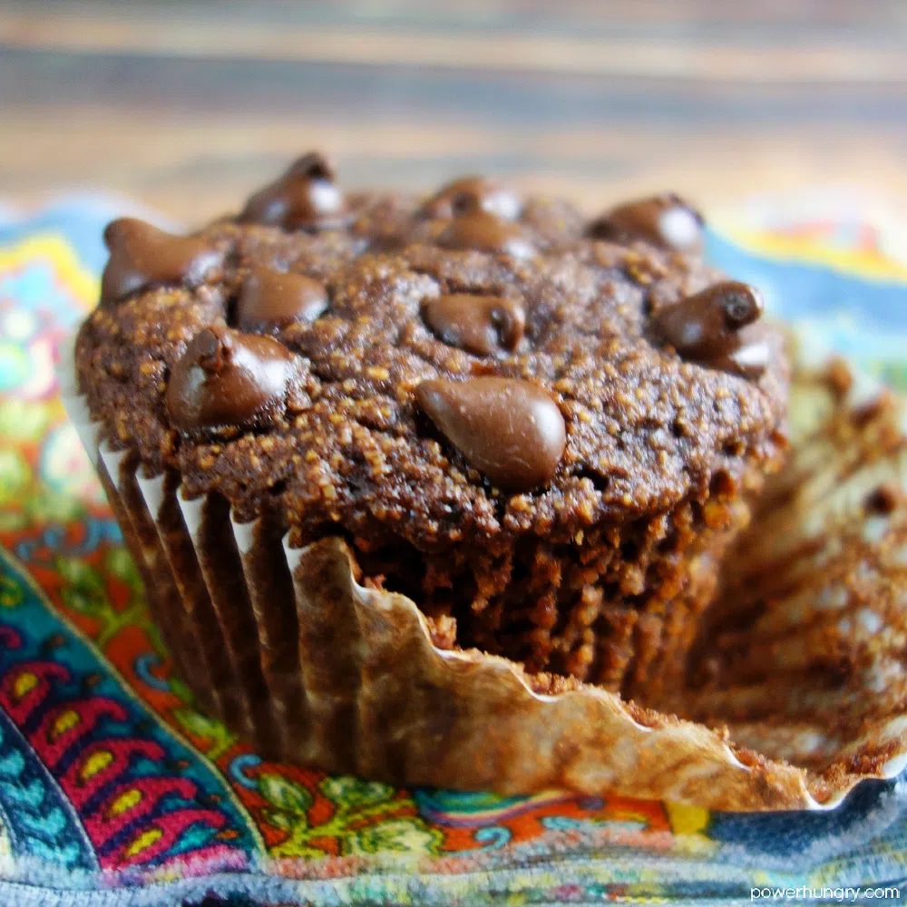 close up of a double chocolate muffin with the muffin liner pulled part of the way off of the muffin
