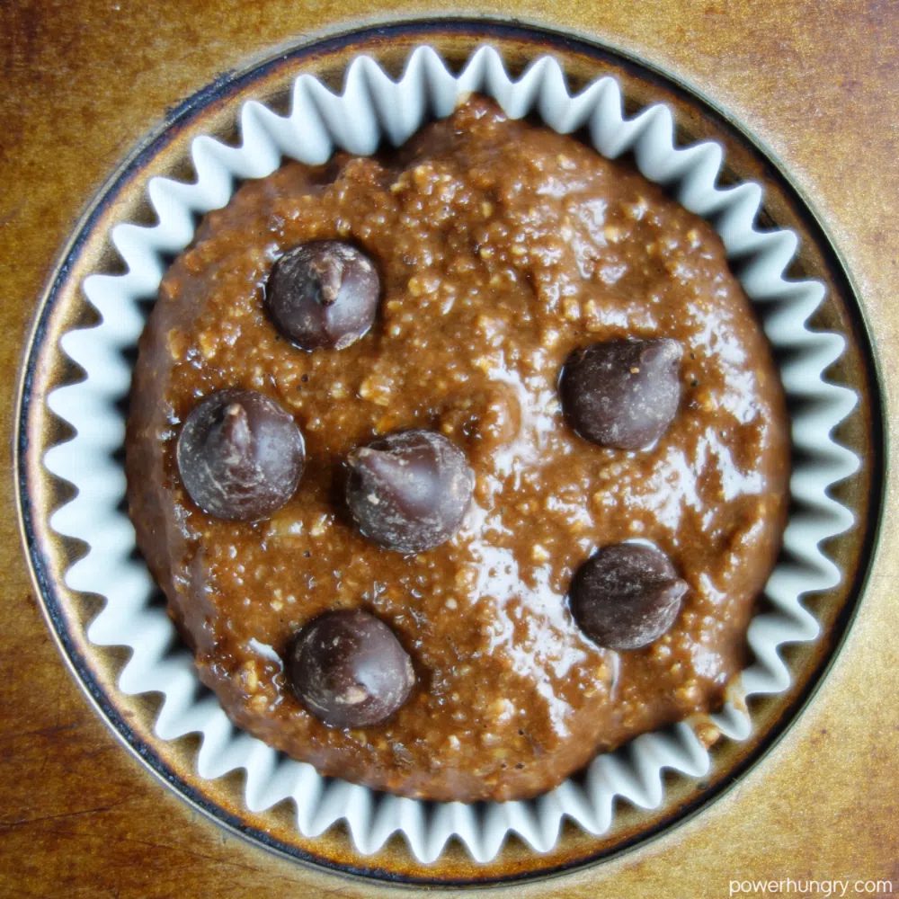 overhead shot of a white muffin liner in a muffin tin, filling with chocolate batter