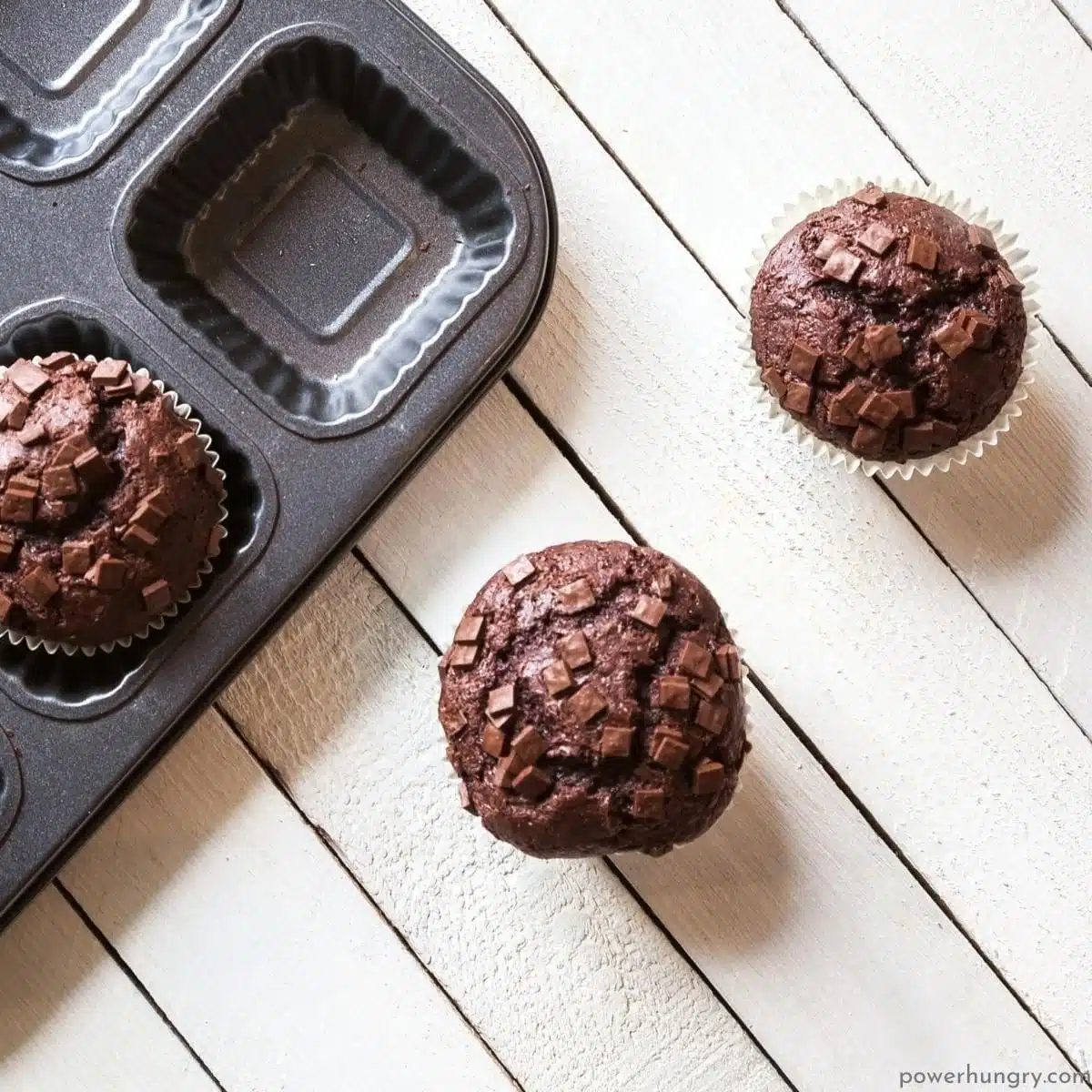 teff muffins on a white wood background
