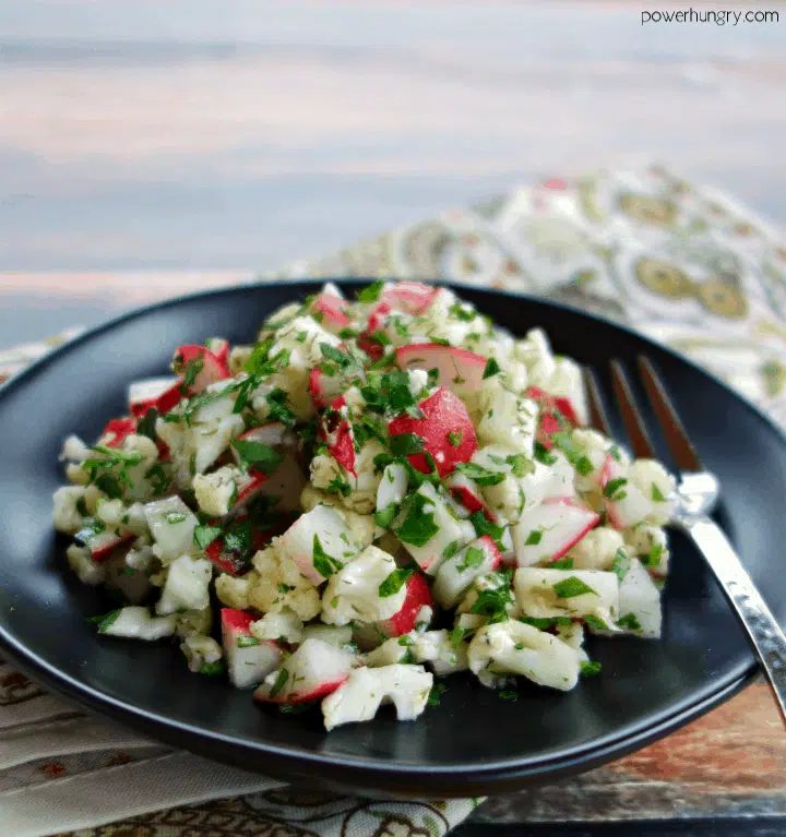 chopped radish & cauliflower salad on a black plate