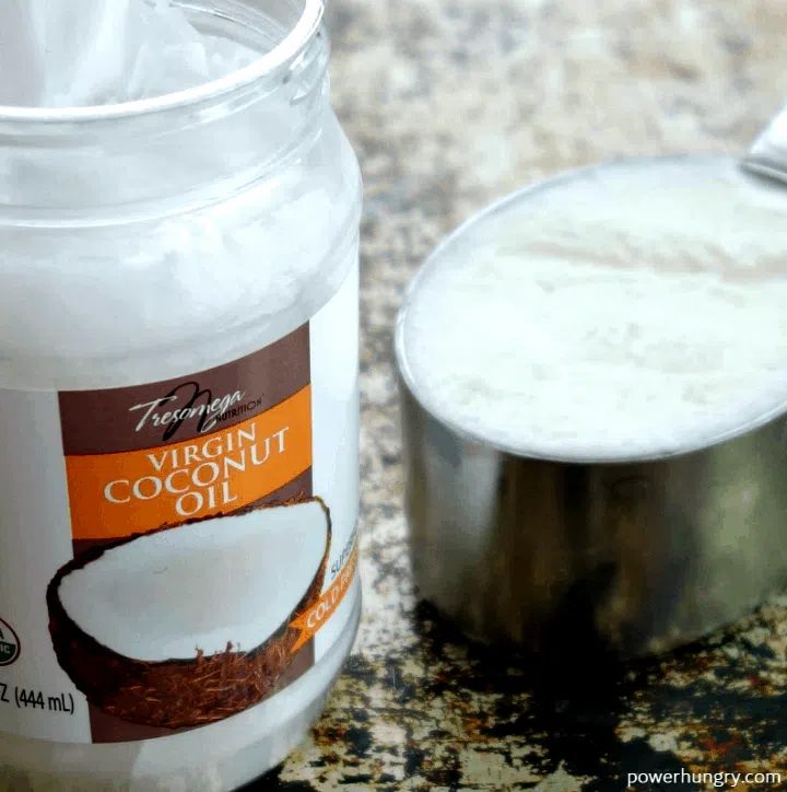 close up of a jar and a measuring cup full of virgin coconut oil