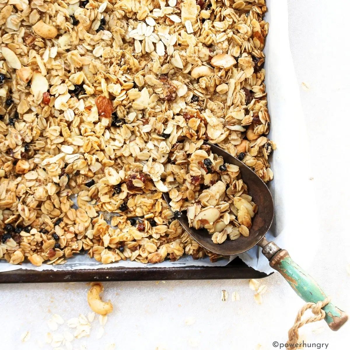 coconut oil granola on a baking sheet with a scoop