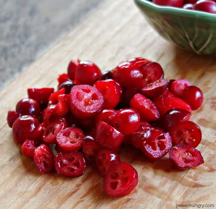 sliced fresh cranberries on a wooden cutting board