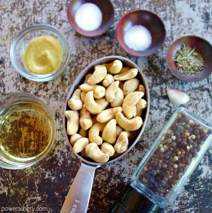Ingredients for creamy cashew salad dressing, including rawcashews, vinegar, garlic, mustard and herbs