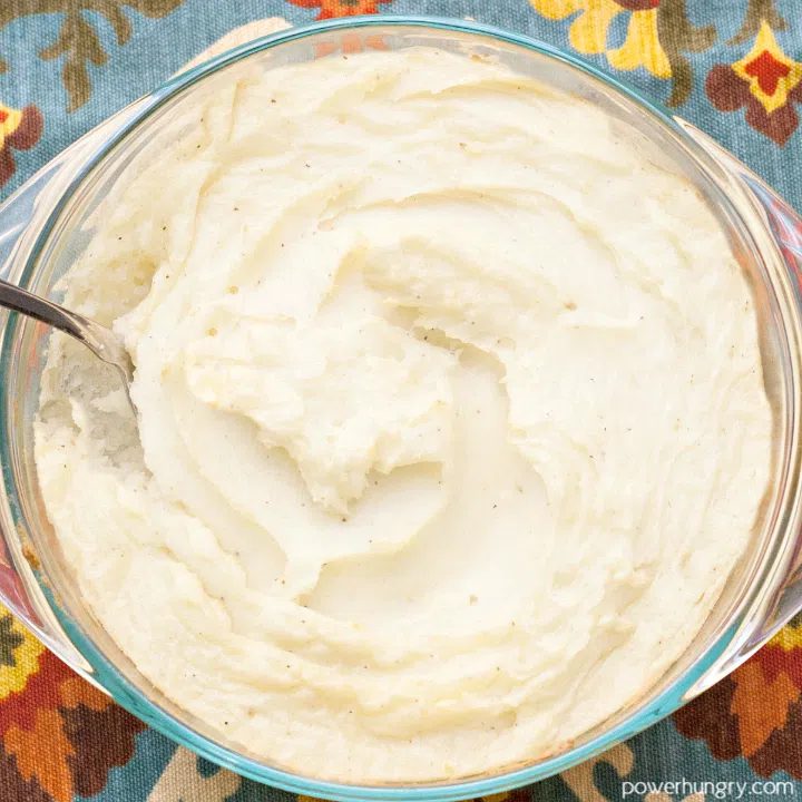 overhead shot of vegan creamy parsnip mash in a glass bowl atop a colorful napkin