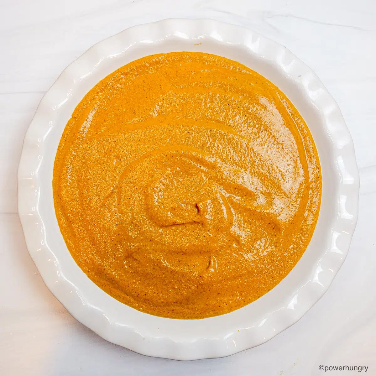 pumpkin pie mixture in white pie dish