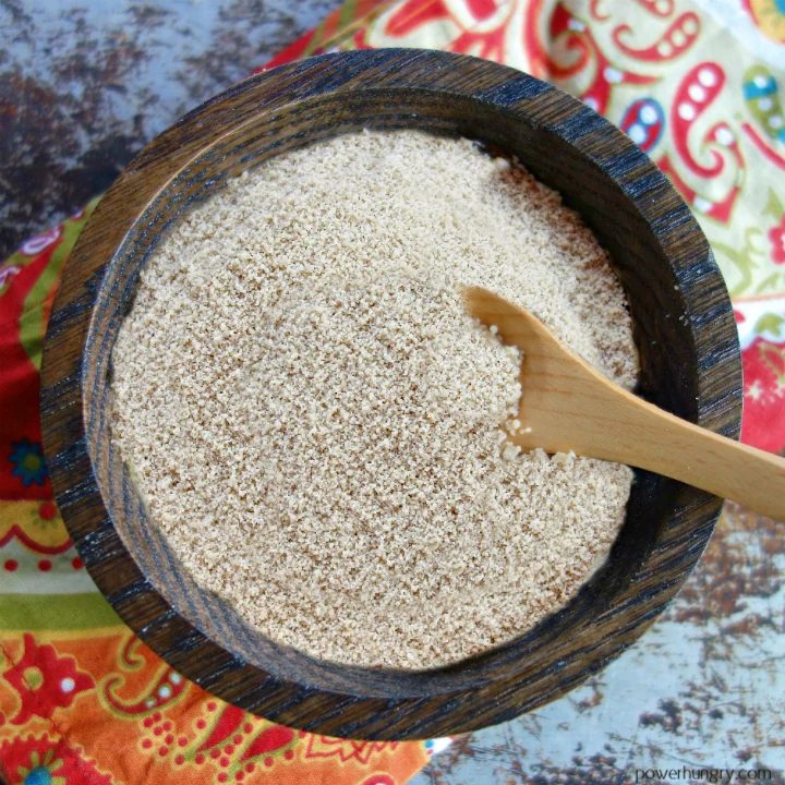 sunflower seed flour in a dark wood bowl atop a colorful napkin