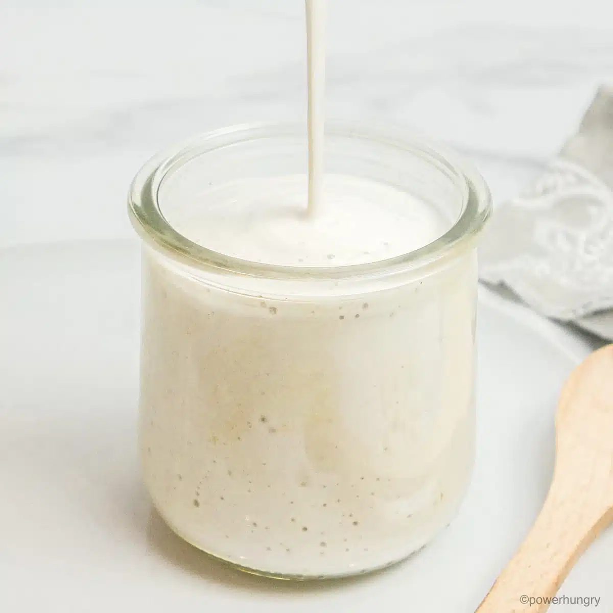 glass jar getting filled with a stream of cashew cream