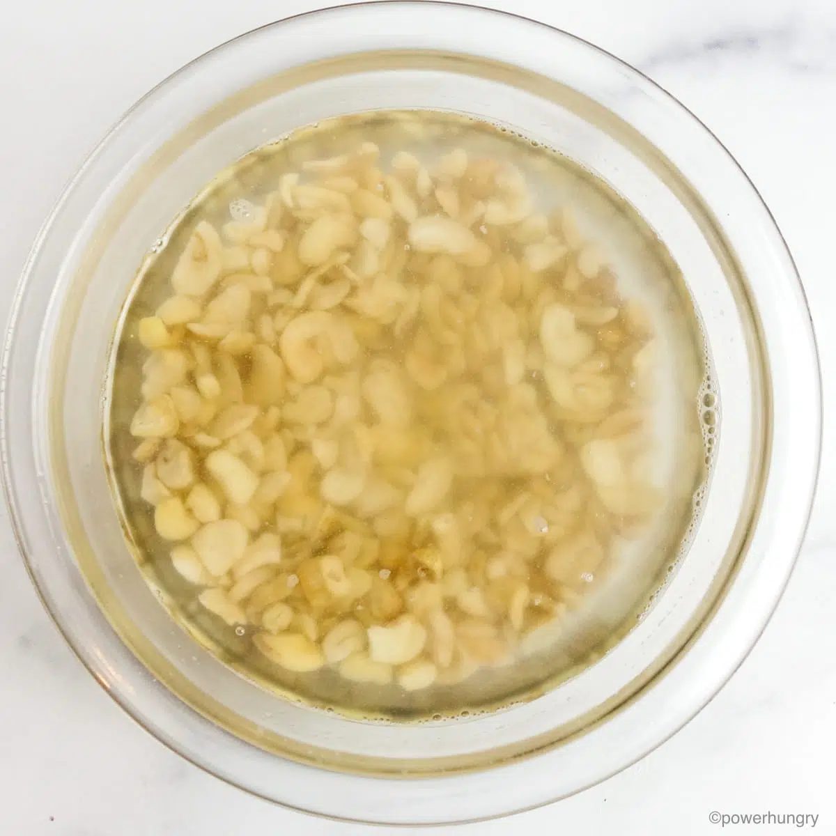 cashews soaking in boiling water, in a clear glass bowl