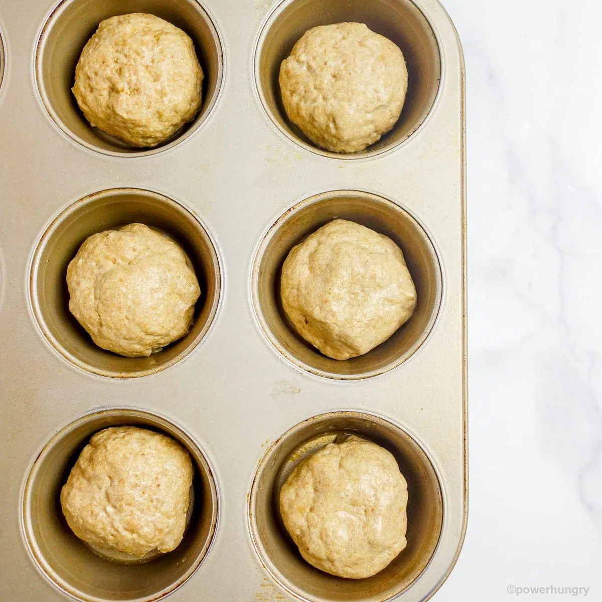 six flax dough balls in the cups of a standard size muffin tin