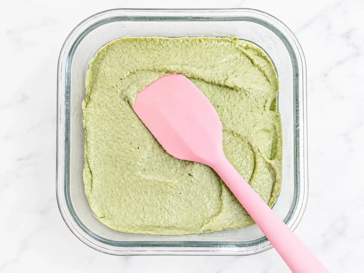 spreading and smoothing pumpkin seed tofu mixture into glass dish