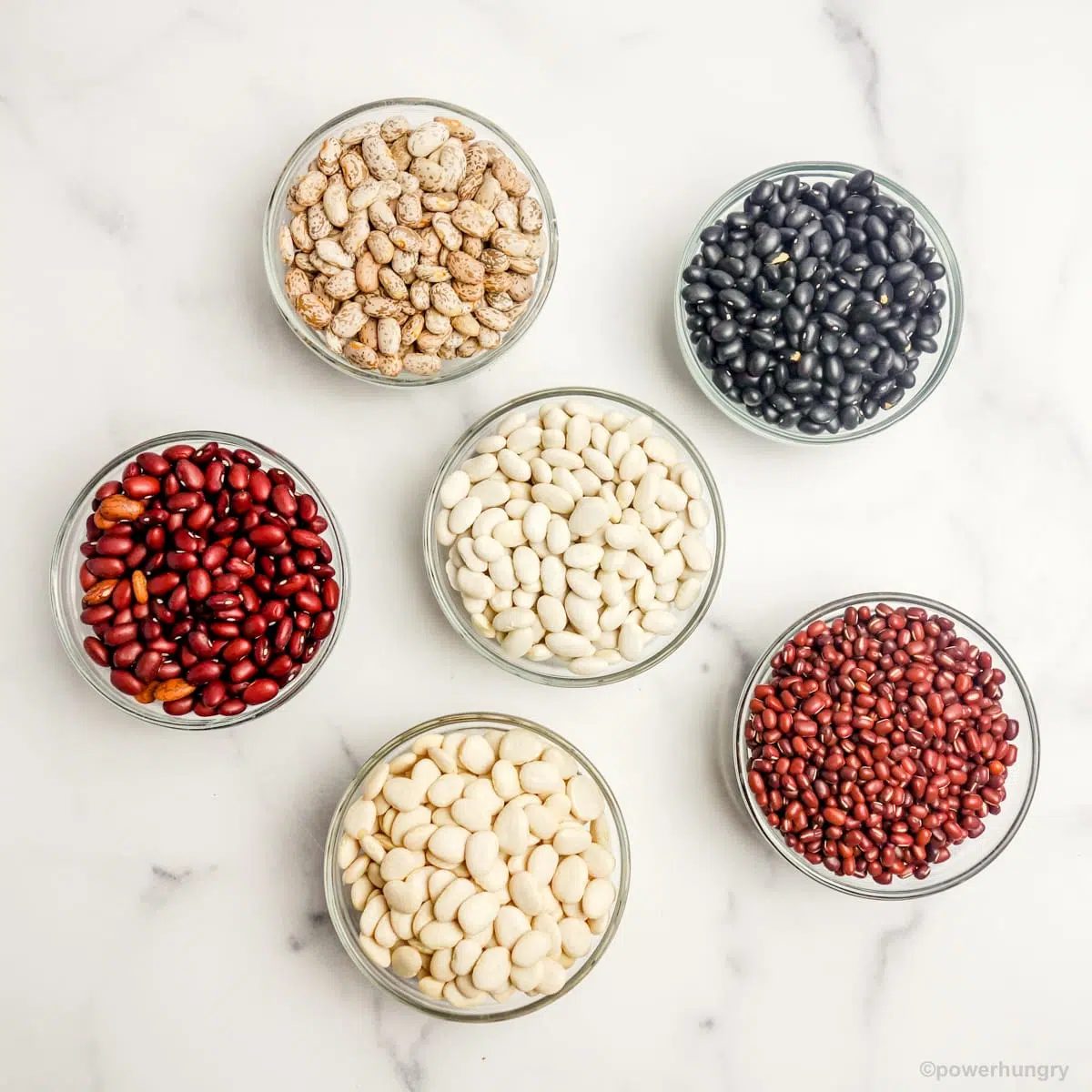 overhead shot of multiple glass bowls filled with various dried beans