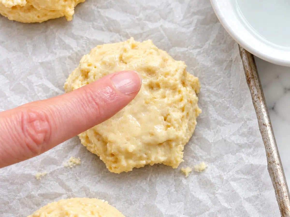 scooped and portioned vegan almond flour biscuits getting tops smoothed with water