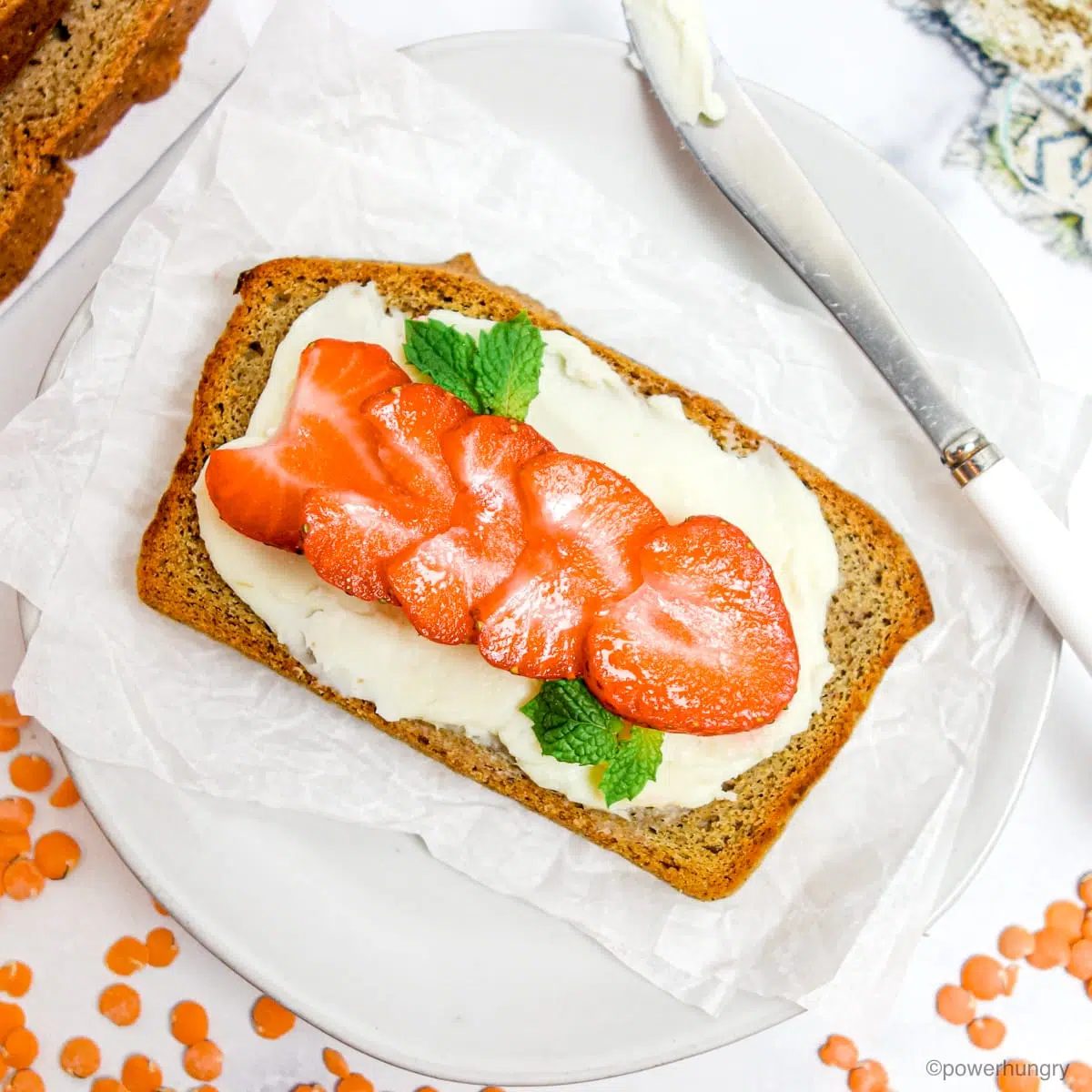 a slice of red lentil sandwich bread spread with vegan cream cheese and topped with strawberries