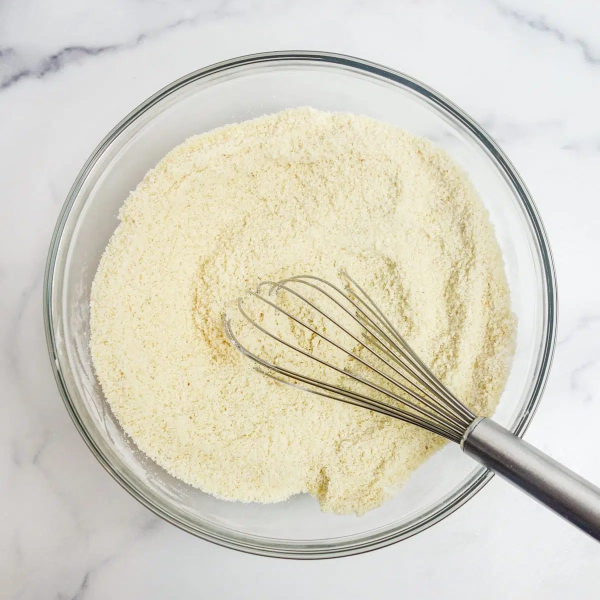 overhead shot of a glass bowl filed with whisked almond flour scone ingredients