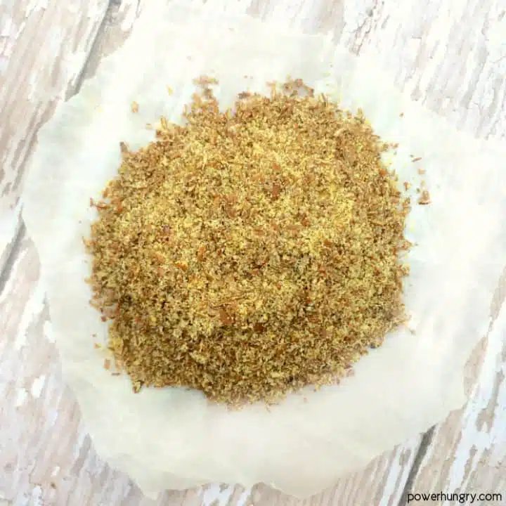 pile of golden flaxseed meal on a piece of parchment paper