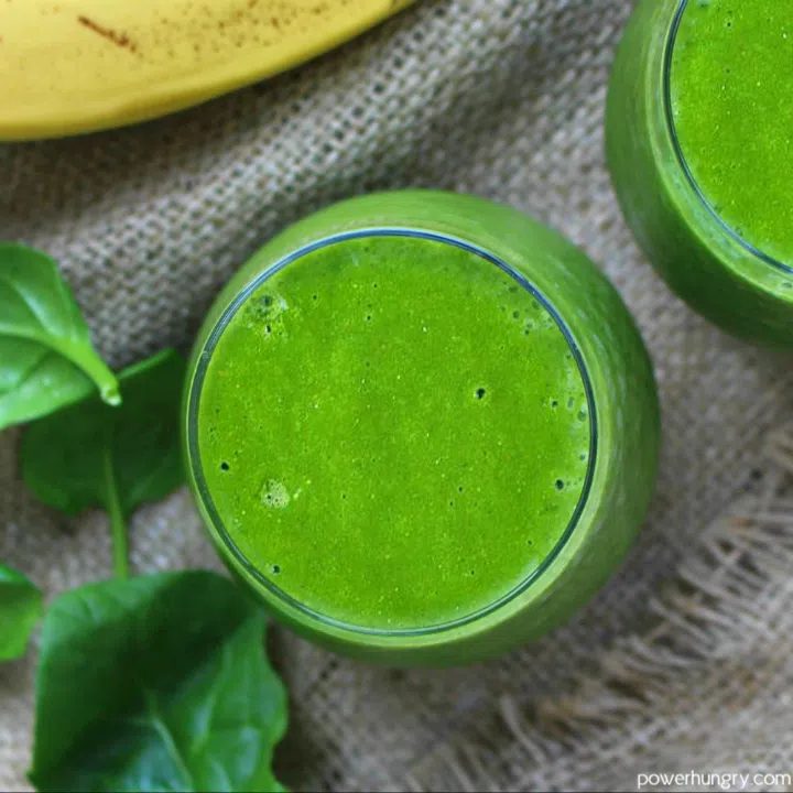 green smoothie on a piece of bulap with a banana and spinach in background
