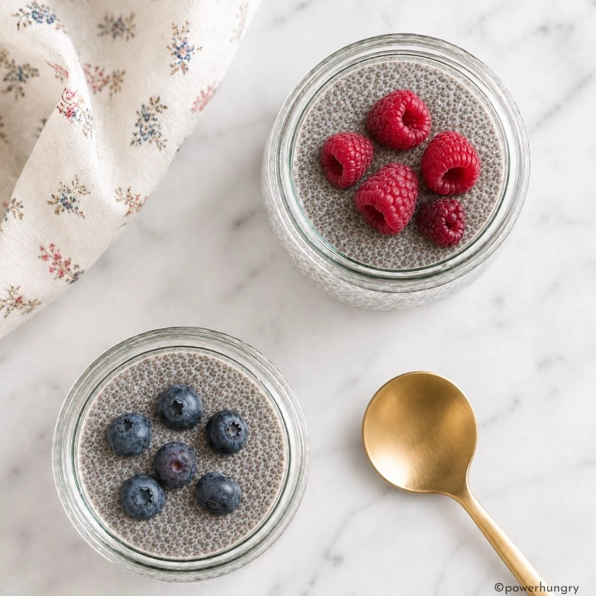 overhead shot of two jars of chia seed pudding topped with berries