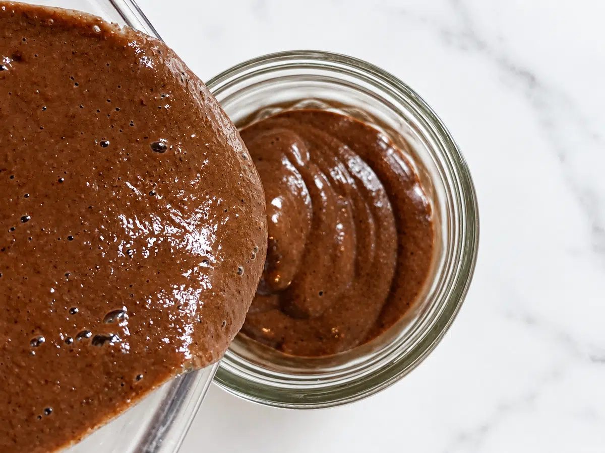 portioning quick blended chocolate chia seed pudding into glass ramekin