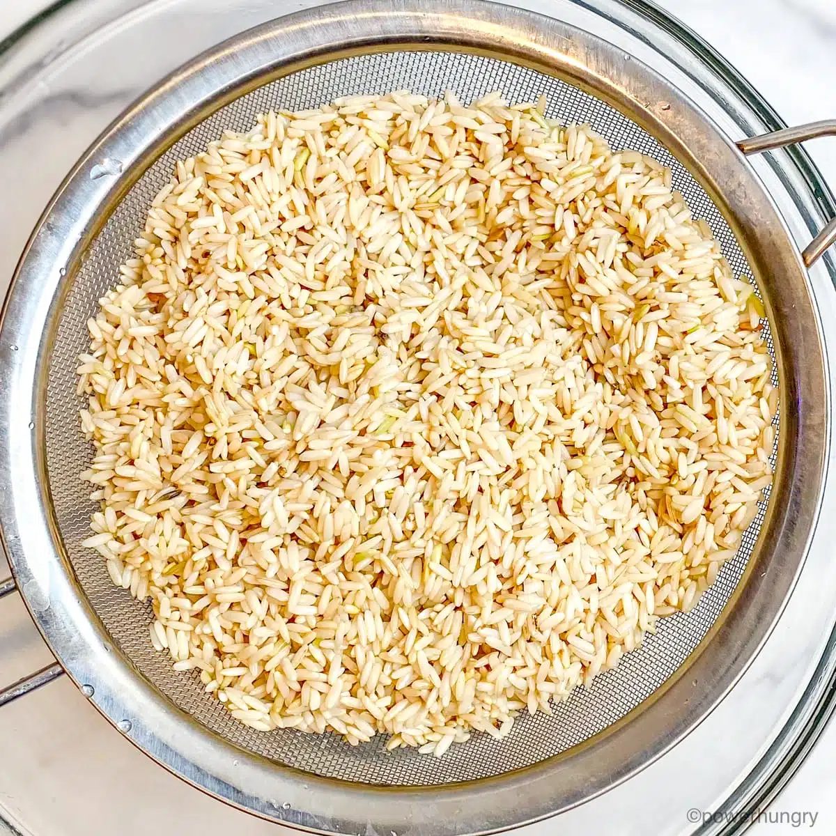 soaked brown rice getting drained in a mesh sieve