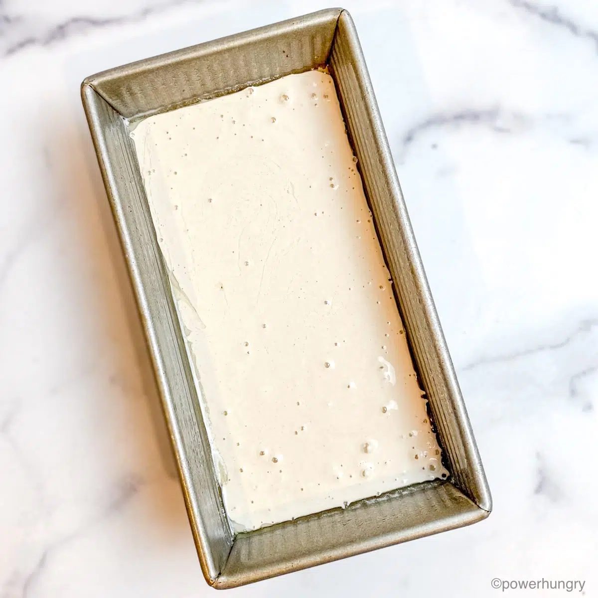 a silver loaf pan filled with gluten-free bread batter
