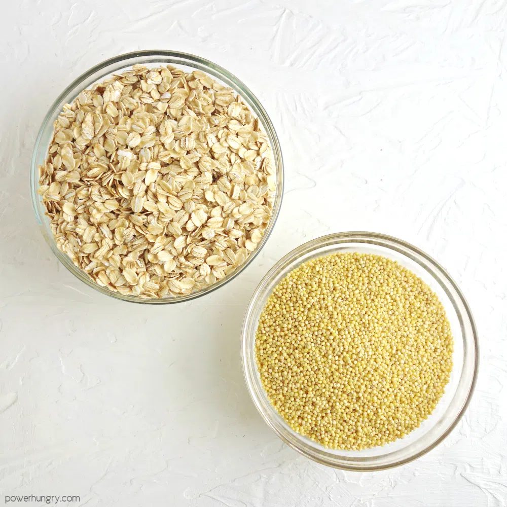 two glass bowls, one filled with rolled oats and one filled with whole millet