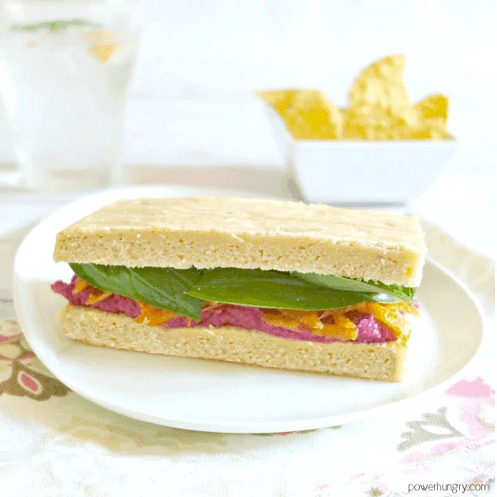 fluffy red lentil bread sliced and used in a sandwich with spinach and hummus