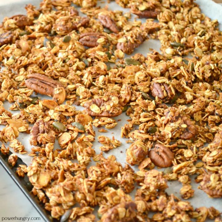 apple pie granola on a parchment paper lined baking sheet