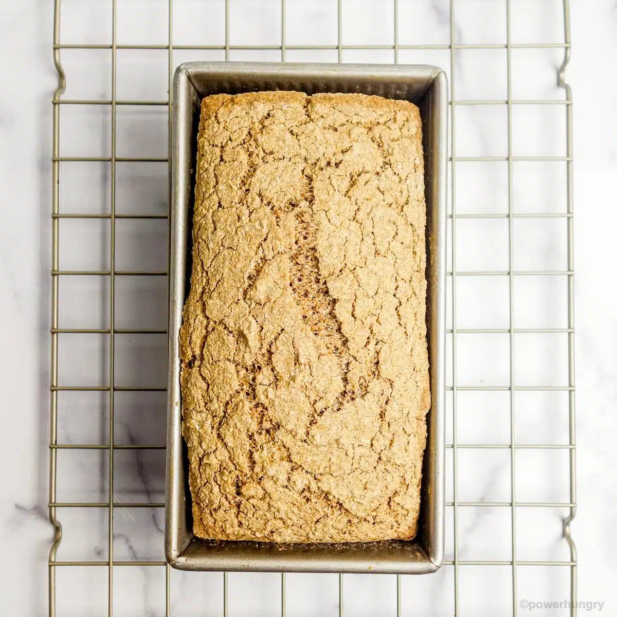overhead shot of a loaf of multigrain sandwich bread on a gold cooling rack