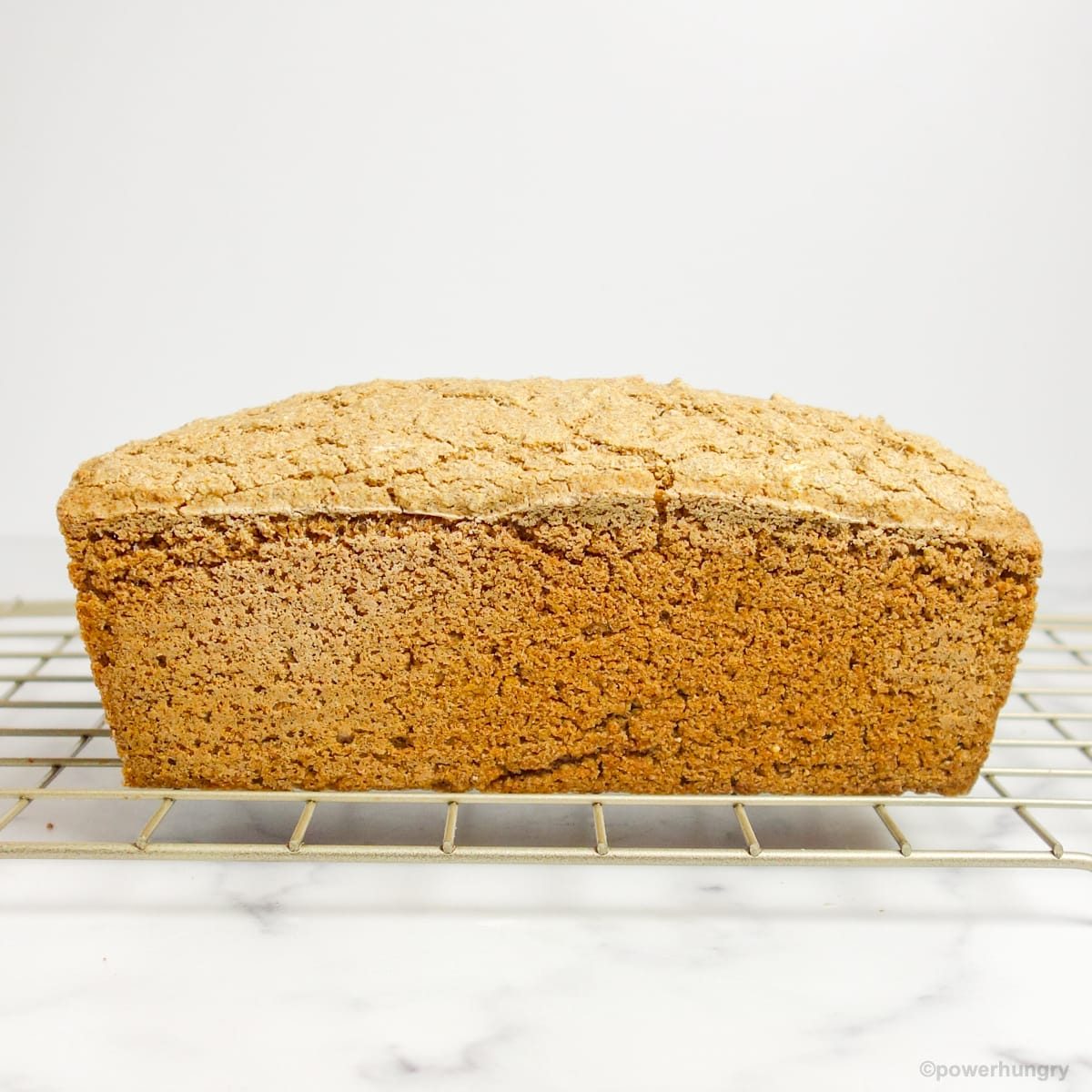 sidewise photo of a loaf of multigrain bread on a cooling rack