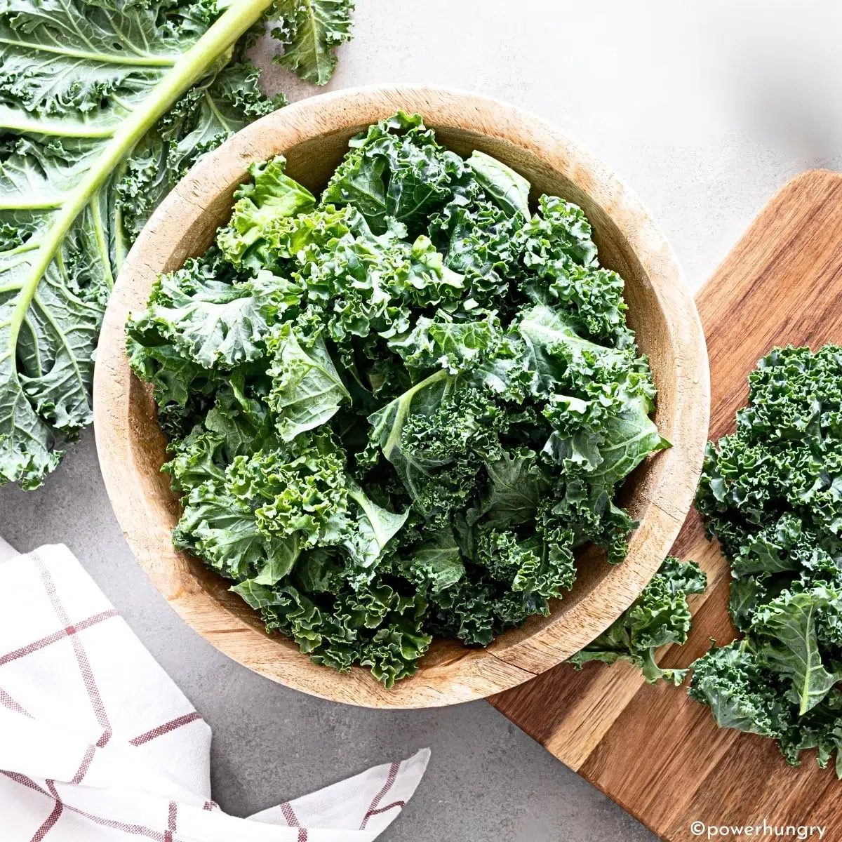 a wooden bowl filled with curly kale leaves