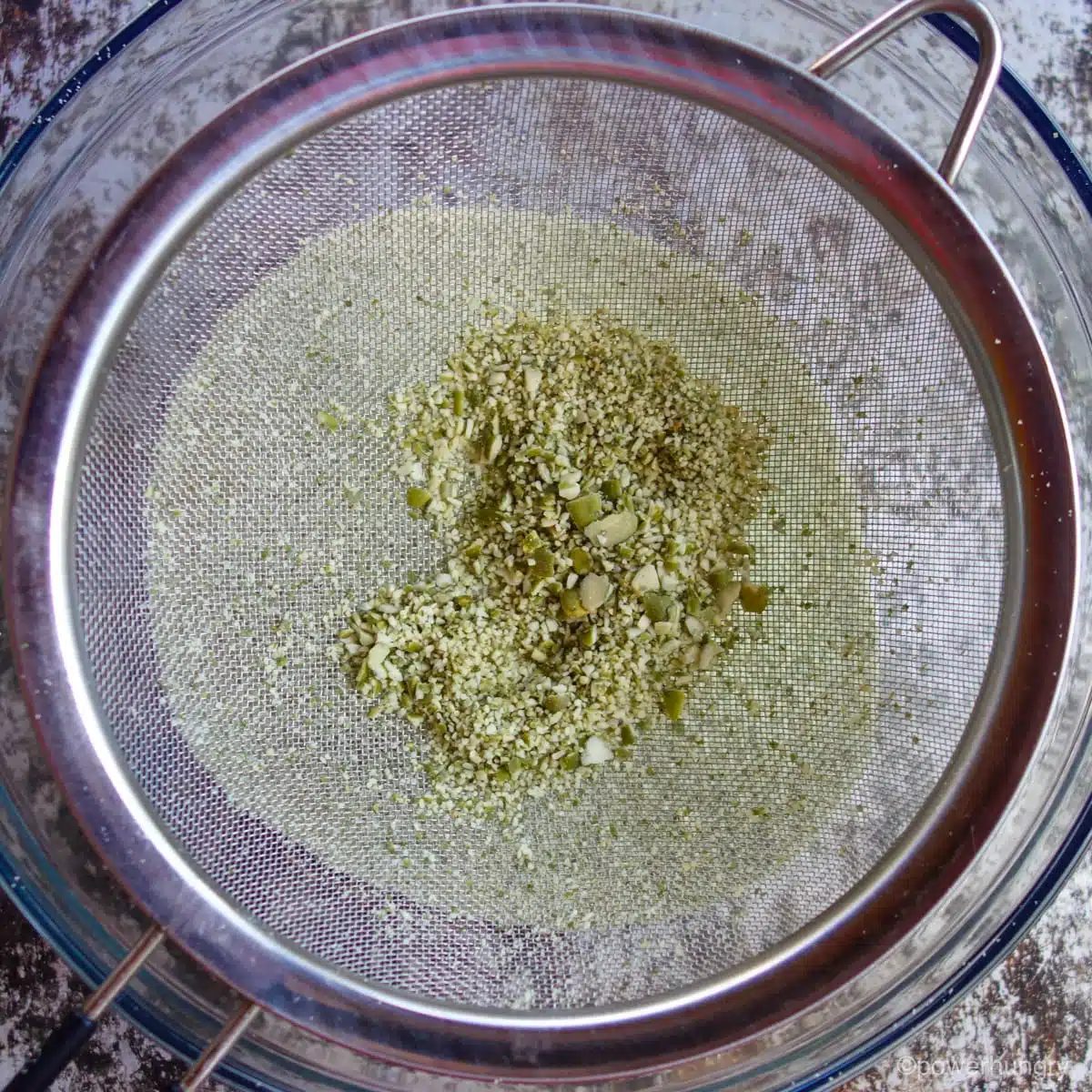 mesh sieve with large pieces of unground pumpkin seeds