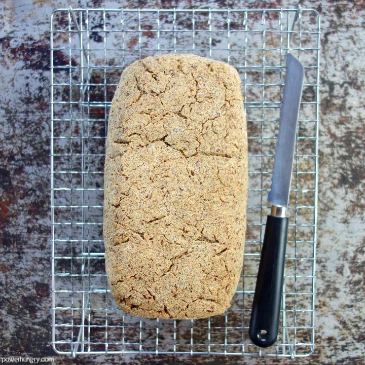 baked vegan keto coconut flour bread on a wire cooling rack with a bread knife alongside