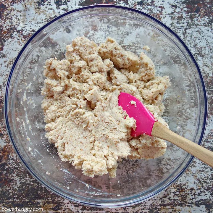 stirred dough for coconut flour bread in a glass bowl with rubber spatula inside