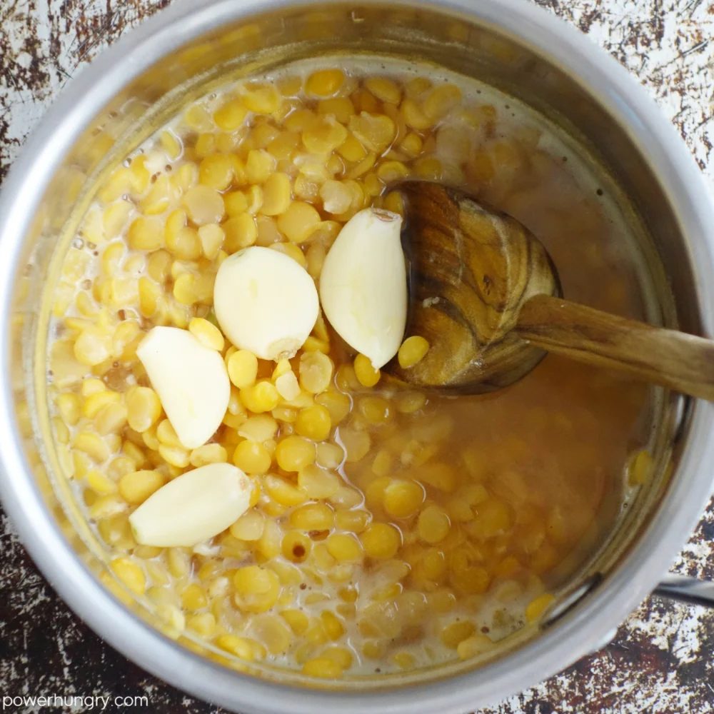 saucepan filled with cooked yellow split peas and garlic cloves