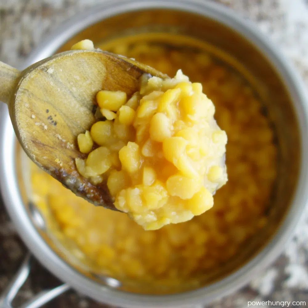 close up of a wooden spoon filled with cooked split peas
