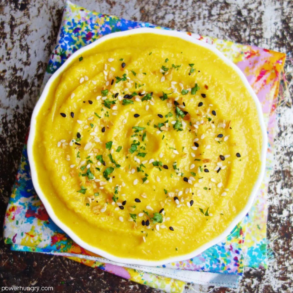 overhead shot of bright yellow split pea dip in a white bowl