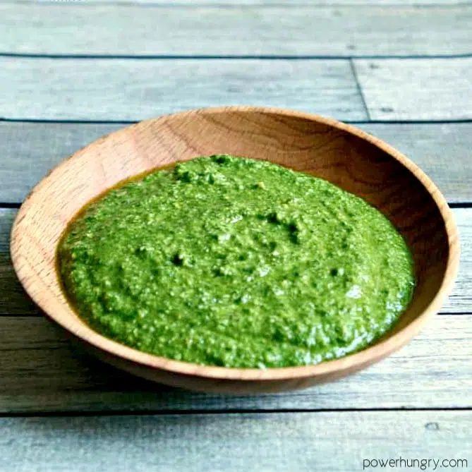 a wooden bowl of arugla pesto or arugula spread on weathered boards