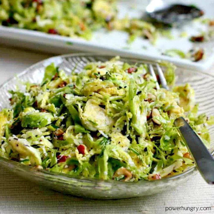 shredded brussels sprouts salad in a salad plate with a serving platter in the background