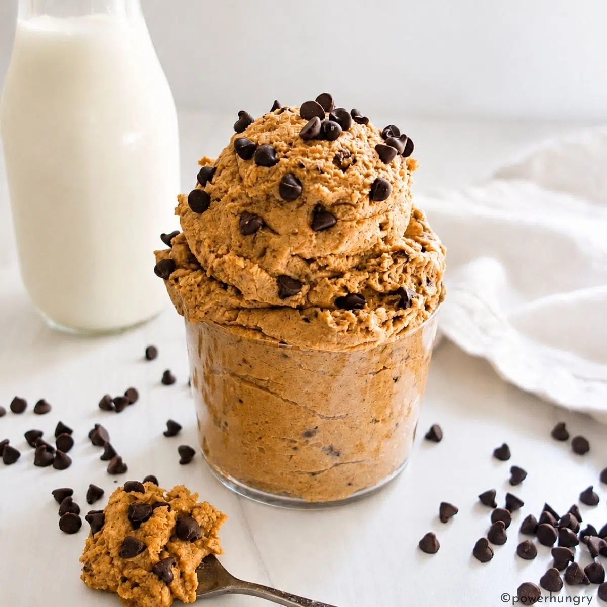 high protein cookie dough with a spoonful of dough and a container of milk nearby
